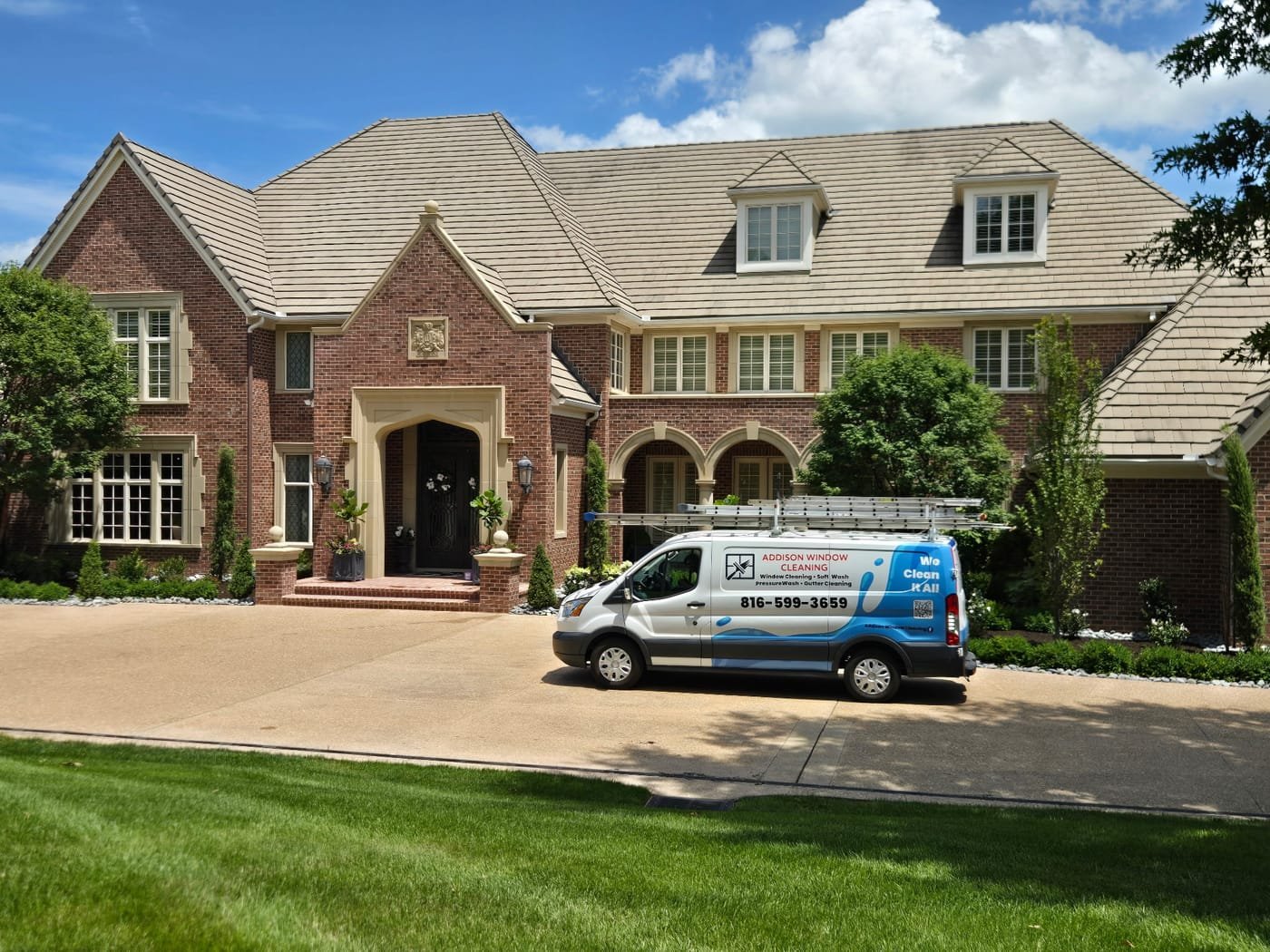 Addison Window Cleaning van parked in the driveway of a large brick home
